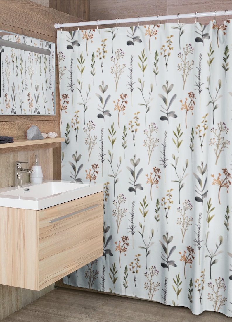 May include: A white shower curtain featuring a repeating pattern of watercolour botanical elements in shades of green, brown, and grey. The bathroom decor includes a wooden vanity and a matching mirror.