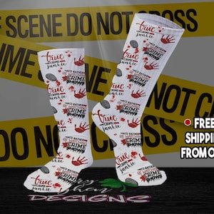 May include: A pair of white socks with a red and black print. The socks feature the text "True Crime Junkie" and "I'd Rather Be Watching Crime Shows".