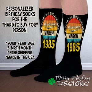 May include: A pair of black socks with a colorful graphic design that says "40 Years of Being Awesome" with the month "March" and year "1985".