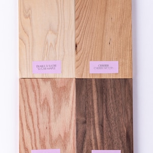May include: Four wood samples, each with a label identifying the type of wood. The samples are arranged in a grid, with sugar maple, cherry wood, red oak, and black walnut.