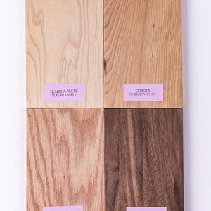 May include: Four wood samples, each with a different grain pattern and color. The samples are labeled with their names in French and English: &Eacute;rable &agrave; Sucre / Sugar Maple, Cerisier / Cherry Wood, Ch&ecirc;ne Rouge / Red Oak, Noyer Noir / Black Walnut.
