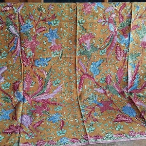 Könnte beinhalten: Ein brauner Stoff mit einem sich wiederholenden Muster aus blauen, roten und grünen Blumenmotiven. Der Stoff hat einen dezenten Glanz und eine weiche Textur.