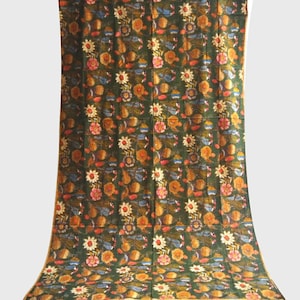 Może przedstawiać: Zielony materiał z powtarzającym się wzorem pomarańczowych, różowych i niebieskich kwiatów. Materiał ma złotą obwódkę.