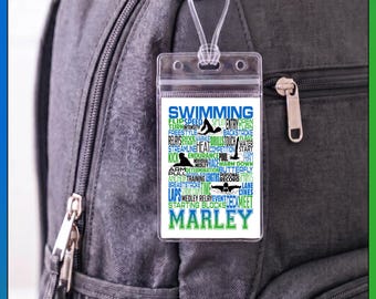 May include: A clear plastic luggage tag with a white insert featuring the word SWIMMING in large blue letters, various swimming-related terms in blue and green text, silhouettes of swimmers, and the name MARLEY in large green letters at the bottom.