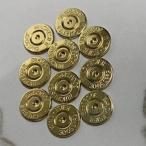 May include: A collection of ten brass Winchester 30-06 SPRG bullet casings. Each casing is gold-colored with stamped text. The casings are arranged on a light-colored surface, showcasing their metallic sheen and detailed markings.