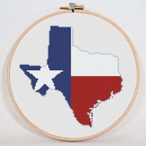 May include: A cross-stitch embroidery of the state of Texas in the shape of the Texas flag. The flag is red, white, and blue with a white star in the blue upper left corner.