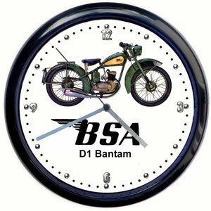 Puede incluir: Un reloj blanco y negro con una imagen de una motocicleta verde y amarilla. La esfera del reloj tiene un logotipo BSA D1 Bantam blanco y negro.