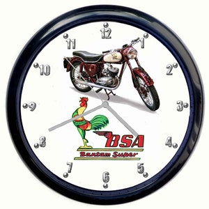 Puede incluir: Un reloj de pared blanco y negro con una motocicleta roja y un logotipo de gallo. La esfera del reloj tiene números y manecillas plateados. El logotipo dice "BSA Bantam Super".