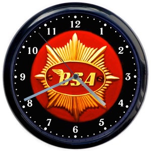 May include: A black wall clock with a red and gold BSA logo in the centre. The clock face has white numbers and a silver metal hour and minute hand.