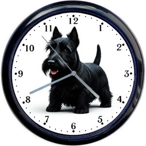 May include: A black wall clock with a white face featuring a black Scottish Terrier dog illustration. The clock has black hands and a black bezel. The numbers are in black, and the clock is round.