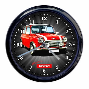Op de afbeelding: Een zwarte wandklok met een rode Mini Cooper auto afbeelding. De wijzerplaat van de klok heeft witte cijfers en een zwarte achtergrond. De auto staat in het midden van de wijzerplaat en de tekst "Mini Cooper" staat onder de auto.
