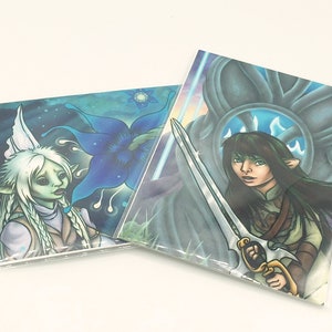 May include: Two fantasy art prints, one featuring a blue flower and a fairy with white wings and long white hair, the other featuring a woman with long dark hair holding a sword in front of a blue and gray background.