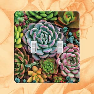 May include: A light switch cover with a colorful succulent plant design. The cover has two toggle switches labeled "OFF".