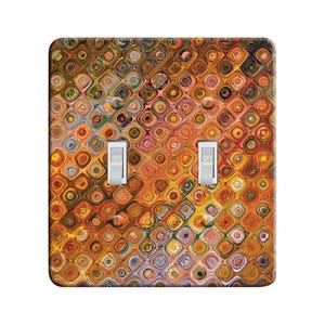 May include: A light switch cover with a colorful abstract pattern of orange, yellow, red, and blue circles and squares. The cover has two toggle switches labeled "OFF".