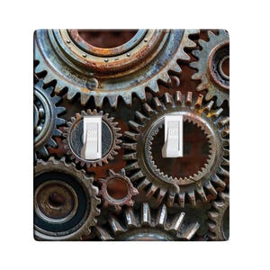 May include: A light switch cover with a design of rusty metal gears. The switch has two toggles labeled "OFF".