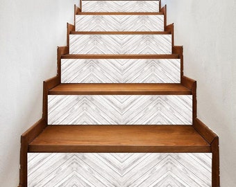May include: Wooden staircase with white and gray chevron pattern stair risers. The steps are made of dark brown wood. The staircase is against a white wall.