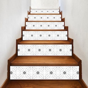May include: A set of gray and white decorative stair treads with a floral pattern. The treads are made of a durable material and are easy to apply.