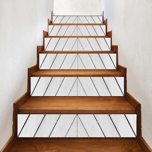 May include: Wooden staircase with white and black geometric design on the risers. The steps are a warm brown color, and the risers feature a white background with black diagonal lines forming a triangle.