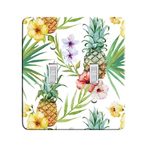 May include: A white light switch cover with a tropical print featuring pineapples, hibiscus flowers, and palm leaves. The switch cover has two toggle switches labeled "OFF".