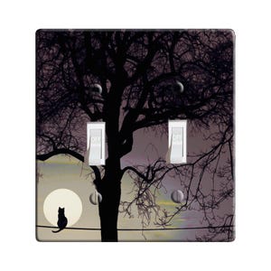 May include: A black cat sits on a wire fence in front of a silhouette of a tree against a purple and yellow sky with a full moon. The words "OFF" are on two light switches.