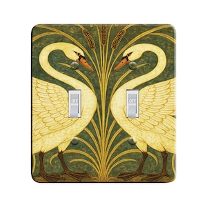 May include: A double light switch cover with a vintage design featuring two white swans facing each other in front of a green and gold floral background. The words "OFF" are printed on the switches.
