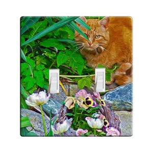 May include: A light orange tabby cat peeks out from behind green foliage. The cat is sitting on a rock with its paws tucked under its body.  The background features a variety of flowers, including white tulips and purple pansies.  The image is a digital painting.