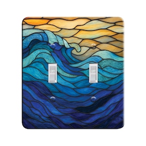 May include: A light switch cover with a stained glass design of blue and yellow waves. The switch cover has two toggle switches labeled "OFF".