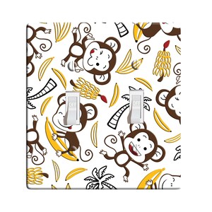 May include: A white light switch cover with a pattern of monkeys and bananas. The switch cover has two toggle switches labeled "OFF".