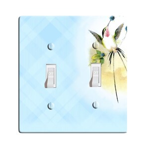 May include: A light blue double light switch cover with a watercolor hummingbird design. The switch cover has the word "OFF" printed on each switch.
