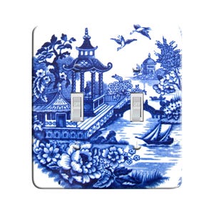 May include: Blue and white porcelain light switch cover with a Chinese landscape design. The switch cover has two toggle switches labeled "OFF".