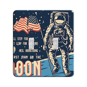 May include: A light switch cover featuring a vintage illustration of an astronaut standing on the moon with an American flag. The text reads "One small step for man, one giant leap for mankind - Neil Armstrong. First man on the moon."