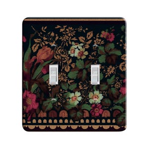 May include: A double light switch cover with a floral pattern. The pattern features a dark background with red, white, and gold flowers. The switch cover has a decorative border with a scalloped edge.