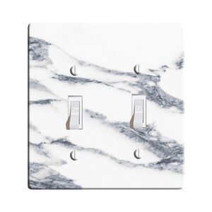 May include: White light switch cover with a gray marble pattern and two toggle switches labeled "OFF".