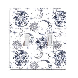 May include: A white light switch cover with a black and white pattern of suns and moons. The pattern is repeated throughout the cover. The words "OFF" are printed on the switch.