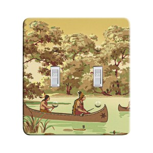 May include: A light switch plate with a vintage design featuring two Native Americans paddling canoes on a lake surrounded by trees. The switch plate has two toggle switches labeled "OFF".