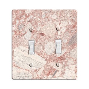 May include: A light switch plate with a pink and white terrazzo pattern. The plate has two toggle switches with the word "OFF" printed on them.