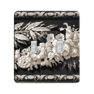 May include: A black and white floral design light switch cover with a decorative border. The switch cover has two toggle switches labeled "OFF".