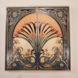 May include: Square ceramic tile with an Art Nouveau design. The tile features a central floral motif in shades of orange, blue, and green, framed by a decorative border. The design is symmetrical and detailed, with a glossy finish.