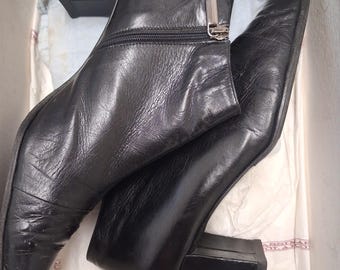 May include: A pair of black leather ankle boots with a square heel and pointed toe. The boots have a zipper closure on the side and are in a white box. The heels are approximately 2 inches high.
