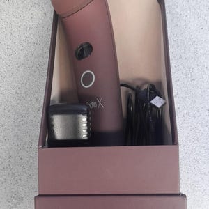 Puede incluir: Un cepillo de dientes eléctrico marrón y negro con el texto "Sonic X" en el lateral. El cepillo de dientes está en una caja marrón con el texto "ZERO GRAVITY" en la parte delantera.