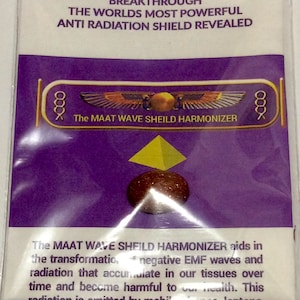 Puede incluir: Un paquete morado y dorado con el texto "BREAKTHROUGH THE WORLDS MOST POWERFUL ANTI RADIATION SHIELD REVEALED" y "The MAAT WAVE SHEILD HARMONIZER" con una pirámide dorada y una piedra marrón.