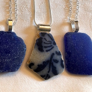 May include: Five necklaces with different blue and white glass pendants. The pendants are all different shapes and sizes, and some have a floral pattern.