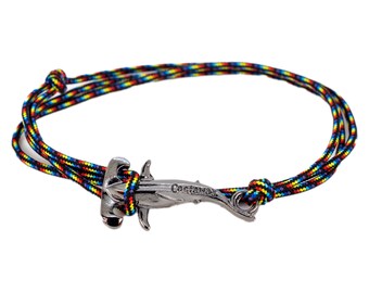 Könnte beinhalten: Ein geflochtenes Armband aus schwarzem, rotem, gelbem und blauem Seil mit einem silbernen Hammerhai-Anhänger. Der Anhänger trägt die Aufschrift "Castaway".