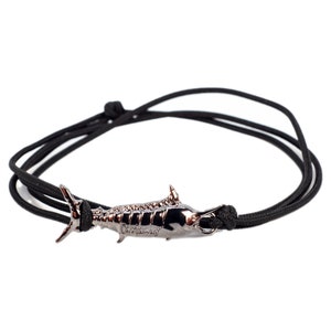 May include: A black cord bracelet with a silver marlin fish charm. The charm has the word "Marlin" engraved on it.