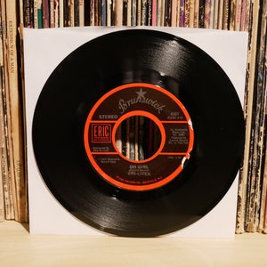 以下が含まれることがあります： 赤と白のラベルが付いた黒いビニールレコード。ラベルには「Brunswick」と「Eric Records」の文字が書かれている。レコードのタイトルは「Oh Girl」で、アーティストは「The Chi-Lites」です。