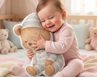 May include: A plush pillow shaped like a teddy bear wearing blue and white striped pyjamas and a matching nightcap. The bear has a light brown fur pattern, closed eyes, and a soft expression, designed as a decorative cushion for a nursery setting.