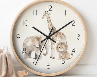 Op de afbeelding: Een ronde wandklok met een licht houten frame. De wijzerplaat toont aquarel illustraties van een olifant, giraf en leeuw. Zwarte wijzers geven de tijd aan. Een decoratief item voor een kinderkamer.