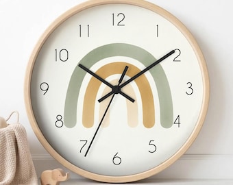 May include: A round wall clock with a light wood frame and a white face. The clock features a central rainbow graphic in muted sage green, mustard yellow, and cream tones. It has black numerals from 1 to 12 and three thin black clock hands.