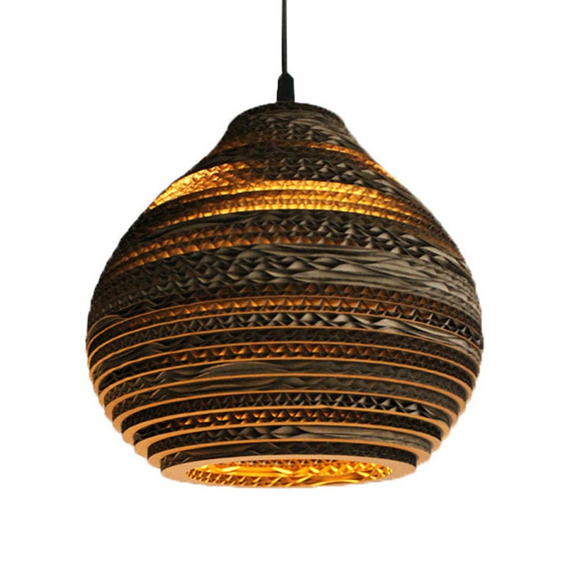 May include: A brown cardboard pendant light with a layered, honeycomb-like design. The light is turned on and emits a warm, yellow glow.
