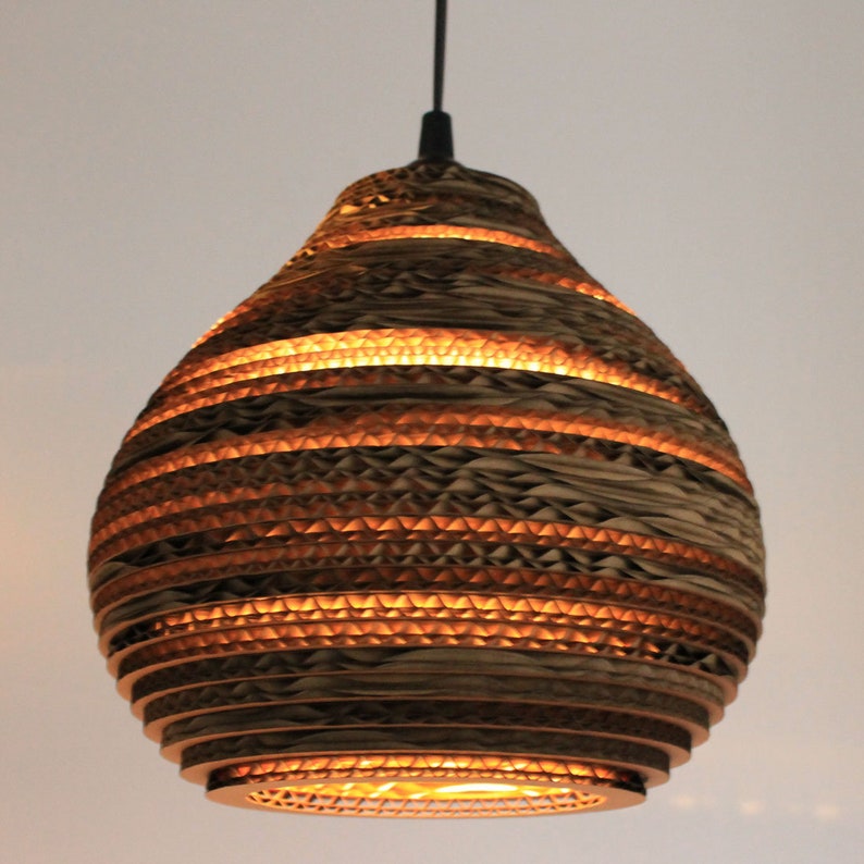 May include: A pendant light made of layered cardboard, with a warm, glowing light emanating from within. The cardboard is arranged in a honeycomb pattern, creating a unique and modern design.
